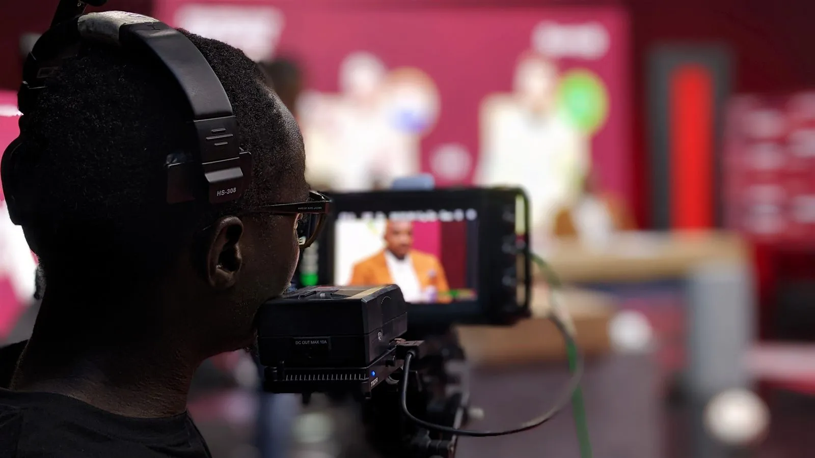 Camarógrafo con auriculares grabando un programa en un estudio de televisión