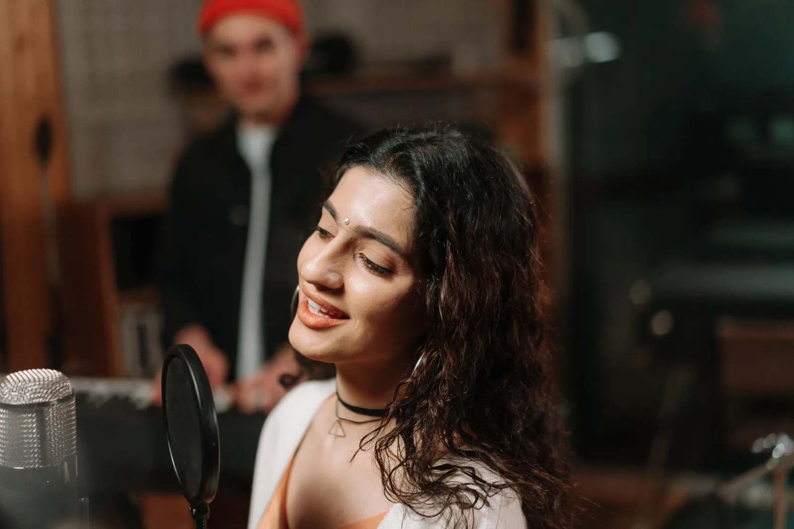 Mujer cantando frente a un micrófono en un estudio de grabación
