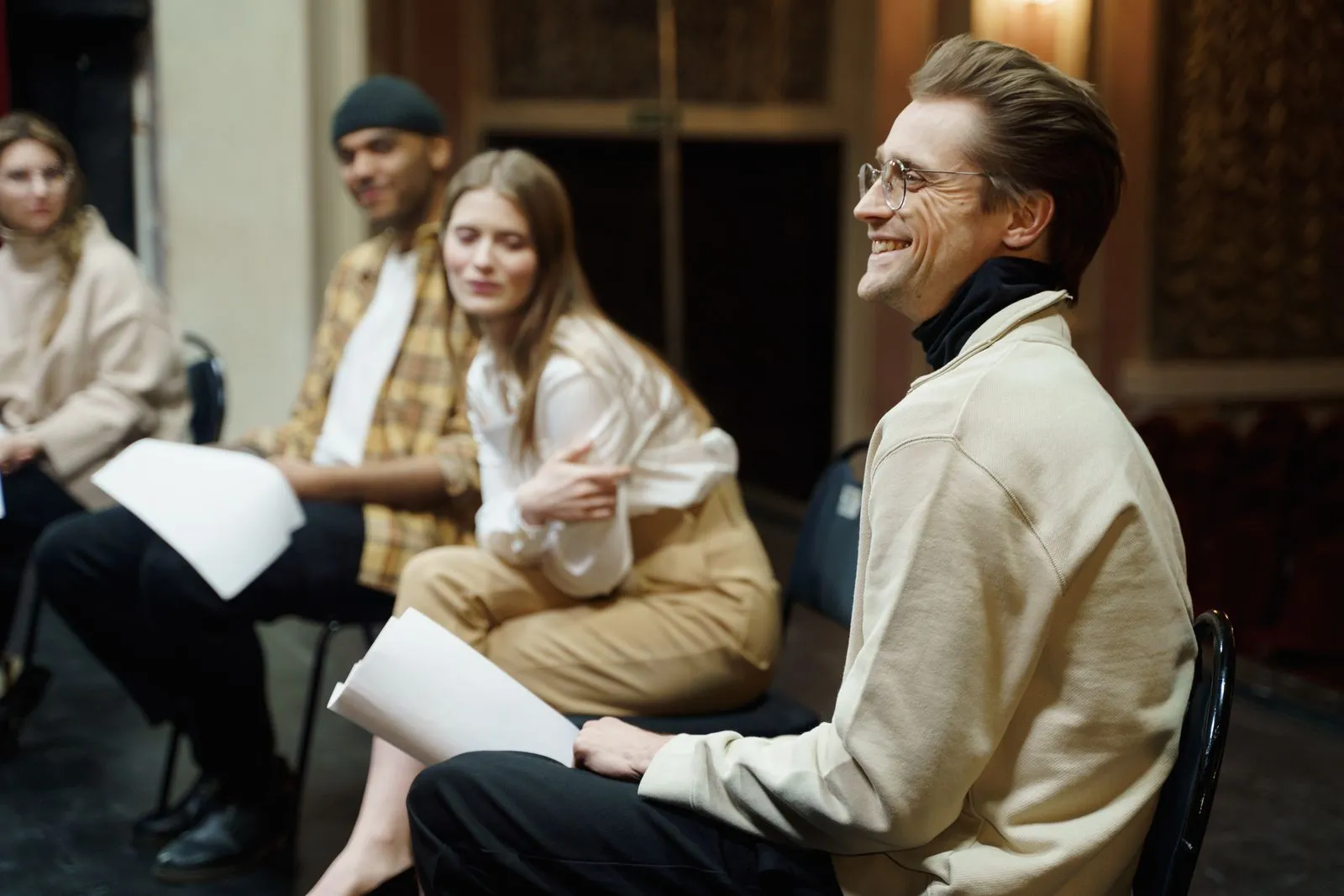 Grupo de actores sonriendo durante un ensayo en un teatro