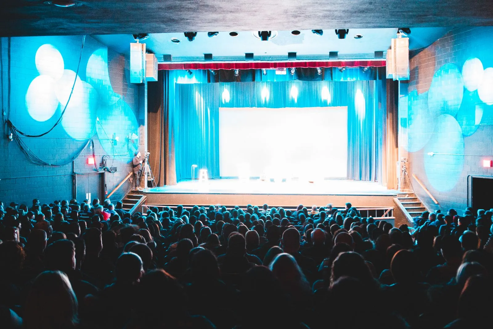 Escena de teatro con el público mirando el escenario iluminado