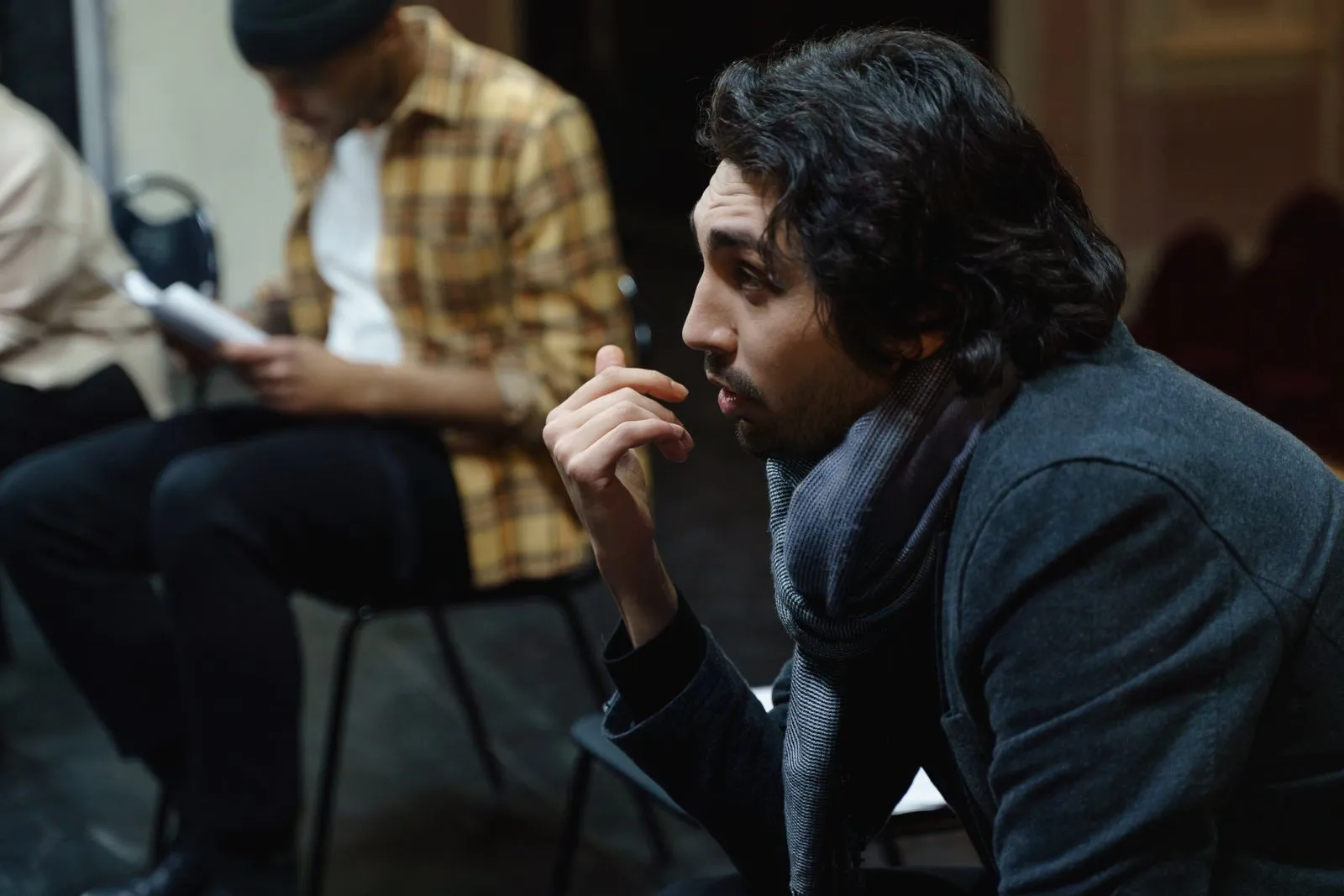 Actor atento durante un ensayo, sentado en la sala